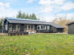 Een modern huis met een ruime patio, een eettafel en terrasmeubilair.