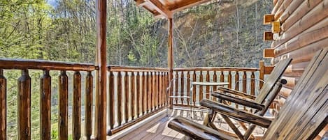 A wooden deck with a railing, a table, and chairs.