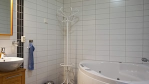 Un baño con una bañera blanca, un lavamanos, un espejo y un perchero para toallas.