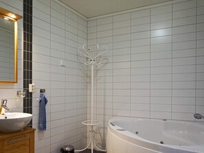A bathroom with a white bathtub, a sink, a mirror, and a towel rack. - 4 Star Holiday Home in Bovallstrand (Bovallstrand)