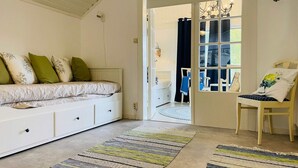 A bedroom with a bed, a chair, a window, and a door leading to another room.