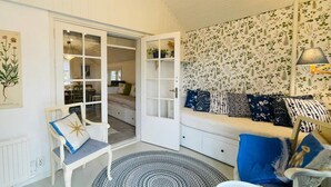 A cozy room with a white bench, a patterned rug, and a wall with floral wallpaper.