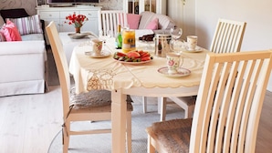 A dining area with a table set for four, featuring a fruit platter, teacups, and a coffee pot. - 5 Person Holiday Home in Frederikstad (Fredrikstad)