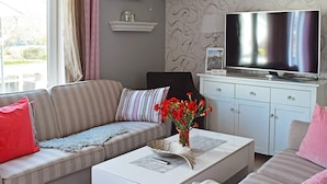 A living room with a sofa, a coffee table, a TV, and a cabinet. - 5 Person Holiday Home in Frederikstad (Fredrikstad)