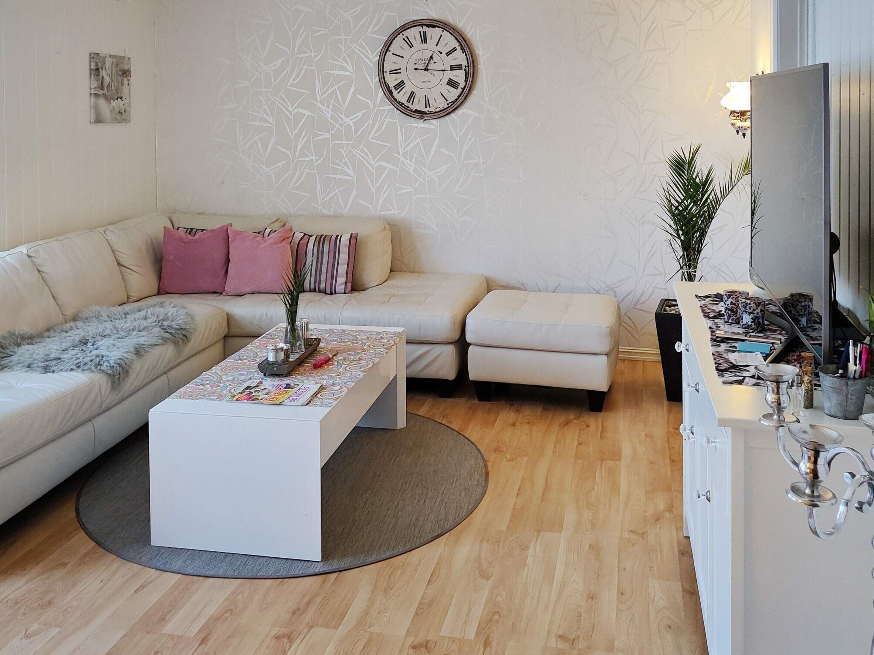 A modern living room with a sofa, a coffee table, a clock, and a cabinet with decorative items.