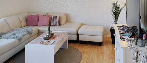 A modern living room with a sofa, a coffee table, a clock, and a cabinet with decorative items.