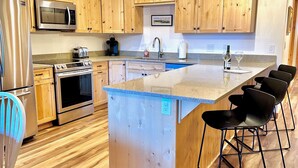 A modern kitchen with wooden cabinets, stainless steel appliances, and a central island with bar stools. - Ask about summer discounts! Walk to Govy/Ski Bowl, Garage parking, Sleeps 8 (Government Camp)