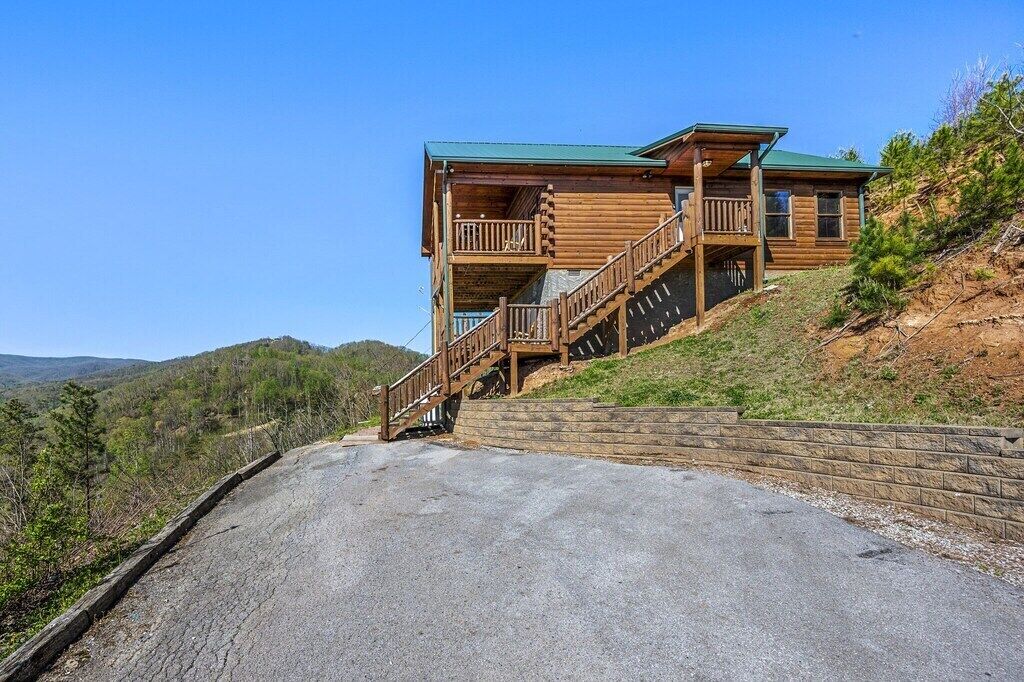 Eine Holzjagdhaus mit Balkon, einer Treppe und Blick auf die umliegenden Hügel.