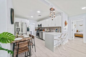 A modern kitchen with white cabinetry, stainless steel appliances, and a central island with seating.