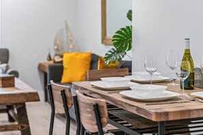 A dining table set with white plates, wine glasses, and a bottle of wine.