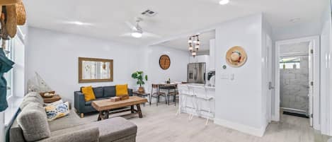Un salon moderne comprenant un canapé, une table basse et un coin repas avec des chaises.