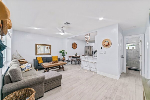 A modern living room with a sofa, coffee table, and a dining area with chairs.