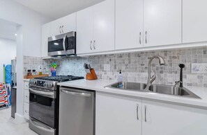 A modern kitchen with white cabinets, a stainless steel range, and a tiled backsplash.