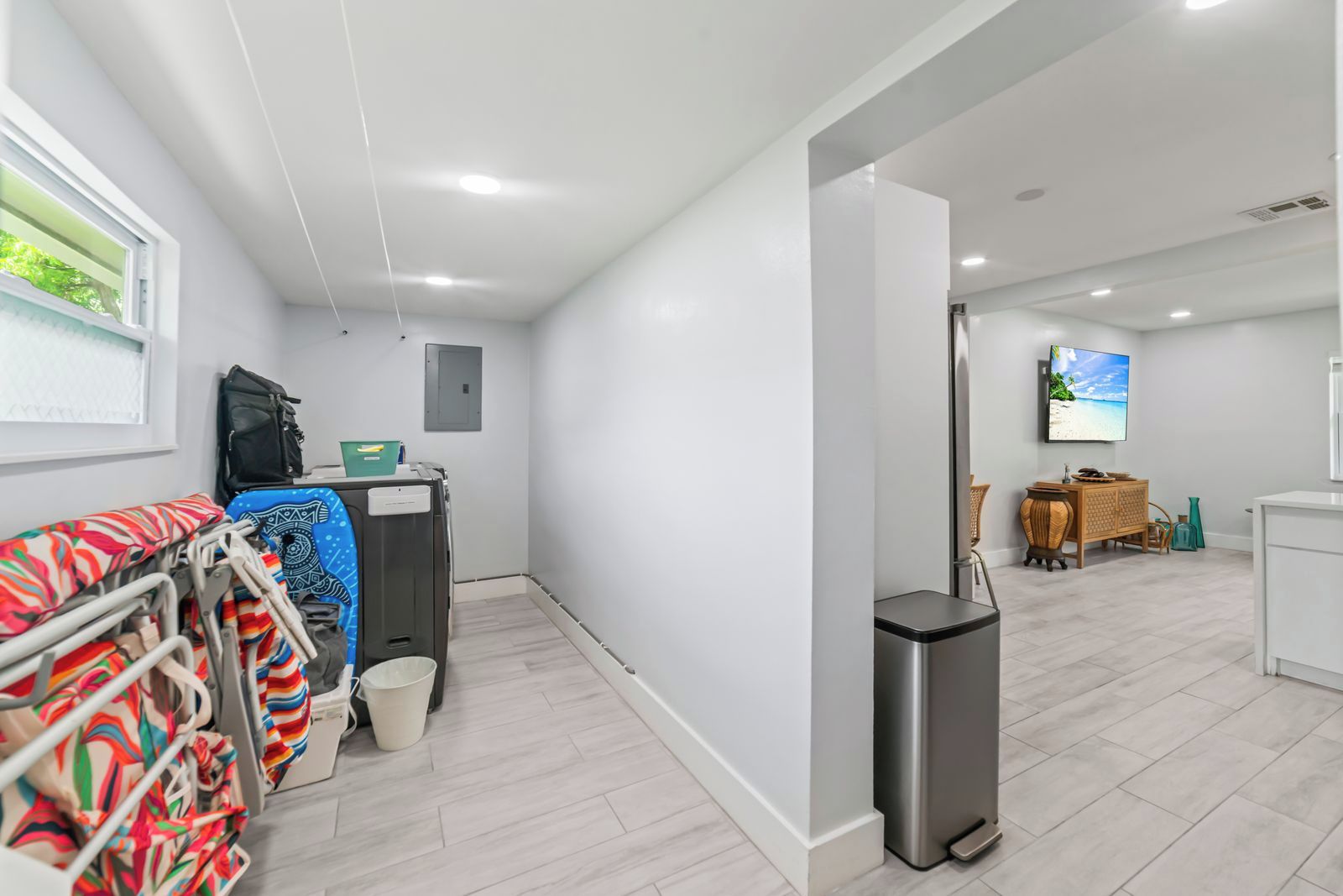 Una habitación moderna y luminosa con televisión de pantalla plana, un pequeño comedor y vista a la playa a través de una ventana.