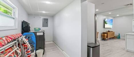 Una habitación moderna y luminosa con televisión de pantalla plana, un pequeño comedor y vista a la playa a través de una ventana.