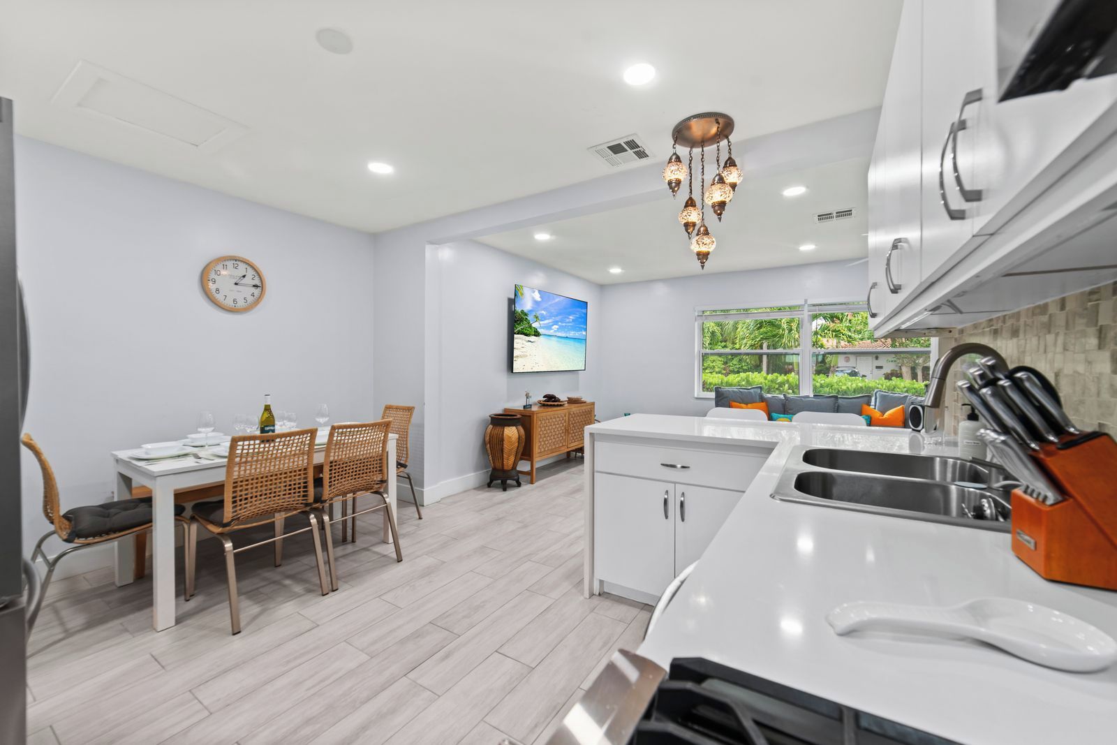 A modern kitchen with white cabinetry, a built-in oven, and a sink with a knife block.