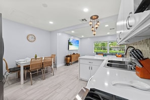 A modern kitchen with white cabinetry, a built-in oven, and a sink with a knife block.