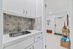 A kitchen with white cabinets, a tiled backsplash, and a stainless steel sink.