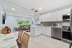 A modern kitchen with white cabinets, stainless steel appliances, and a dining area with a table set for four.