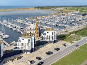 A marina with numerous boats docked, a construction crane, and a modern building with a flat roof. - 5 Star Holiday Home in Wendtorf (Wendtorf)
