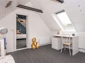 A child's bedroom with a loft bed, a desk, and a chair.