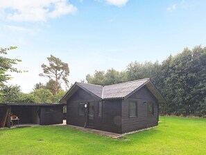 A small, dark-colored wooden house with a sloped roof, a front door, and windows. - 6 Person Holiday Home in Oster Assels (Øster Assels)