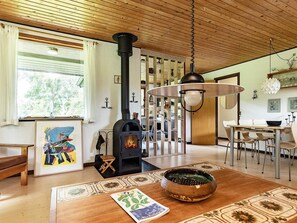 Uma sala de estar aconchegante com lareira, teto de madeira e um espaço de jantar com mesa e cadeiras.