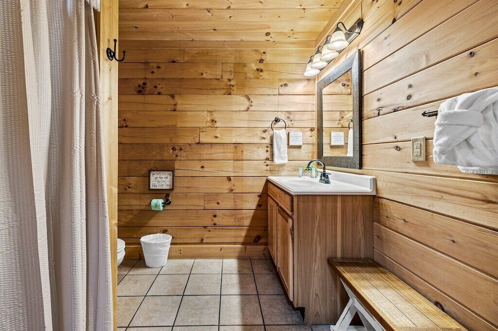 A wooden cabin bathroom with a sink, mirror, and towel rack.