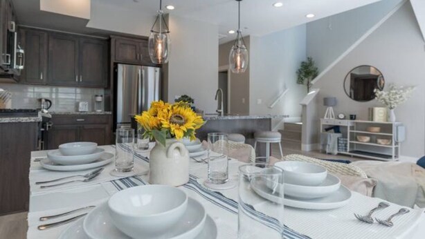 A modern kitchen with dark cabinets, stainless steel appliances, and a dining area set for a meal. - Modern Mountain 3BR Near Donner Lake & Trails (Truckee)
