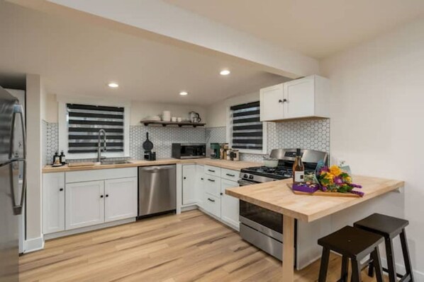 A modern kitchen with white cabinets, stainless steel appliances, and a wooden countertop.