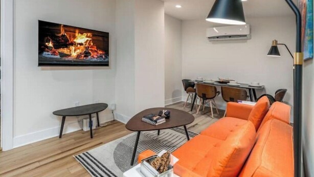 Ein modernes Wohnzimmer mit Flachbildfernseher, einer Couch, einem Couchtisch und einem Essbereich mit Stühlen und einem Tisch.
