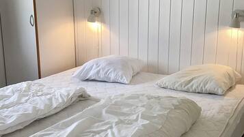 A bed with white bedding and two wall-mounted light fixtures.