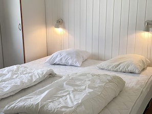 A bed with white bedding and two wall-mounted light fixtures.