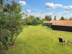 A grassy yard with a building and a bench. - 14 Person Holiday Home in Vaeggerlose (Vaeggerlose)