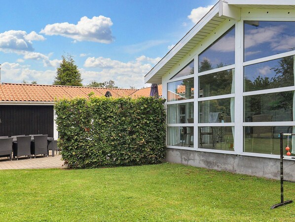 A modern building with large windows, a well-maintained lawn, and outdoor furniture.
