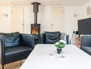 A living room with a black wood-burning stove, leather sofas, a white table, and a potted plant. - 14 Person Holiday Home in Vaeggerlose (Vaeggerlose)