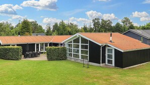 A row of black buildings with red roofs, a grassy lawn, and a clear sky. - 14 Person Holiday Home in Vaeggerlose (Vaeggerlose)