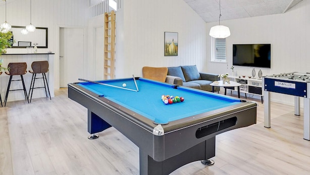 A modern indoor recreational area with a pool table, a foosball table, and a bar area with stools. - 5 Star Holiday Home in Vaeggerlose (Vaeggerlose)