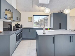 A modern kitchen with grey cabinetry, a central island, and pendant lighting. - 5 Star Holiday Home in Vaeggerlose (Vaeggerlose)