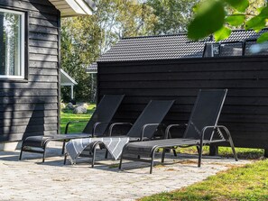 A row of black lounge chairs with metal frames and a blanket on one. - 5 Star Holiday Home in Vaeggerlose (Vaeggerlose)