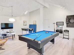 A modern living room with a pool table, a television, and a dartboard.