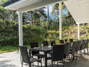 An outdoor patio with a table and chairs, surrounded by greenery and trees.