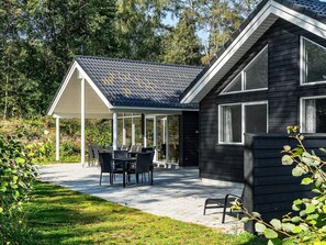 A house with a covered patio area, a dining table with chairs, and a black exterior.