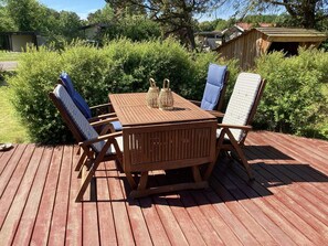 A wooden deck with a table and four chairs. - 4 Star Holiday Home in Dannemare (Dannemare)