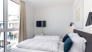 Une chambre d’hôtel moderne dotée d’un grand lit, d’une télévision à écran plat et offrant une vue sur la ville.
