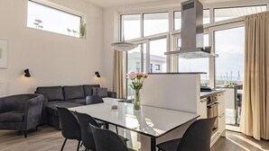 A modern living room with a dining area, large windows, and a view of the sea. - 5 Star Holiday Home in Wendtorf (Wendtorf)