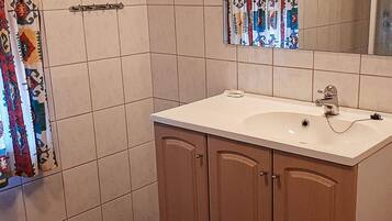 A bathroom with a white sink, wooden cabinets, a towel rack, and a shower curtain.