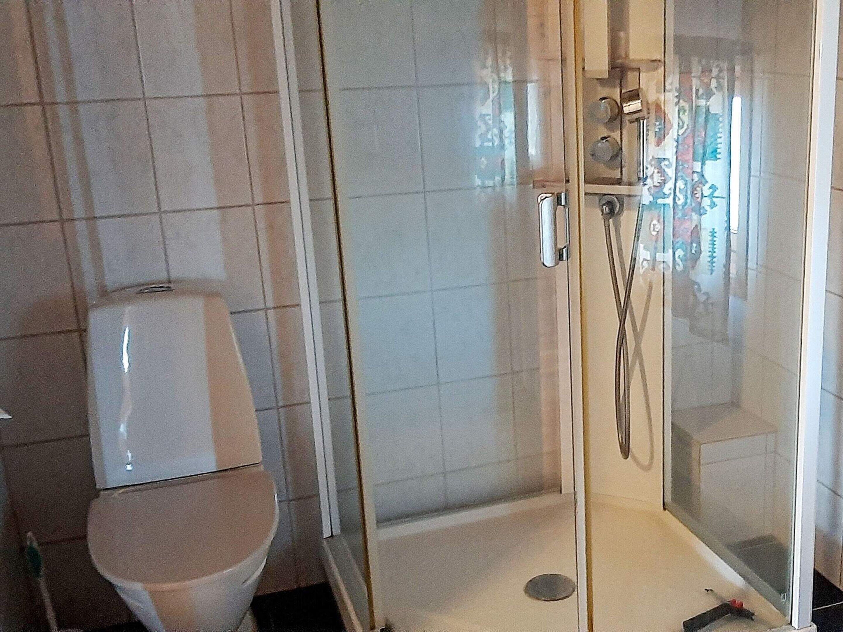 A bathroom with a toilet and a glass-enclosed shower area.