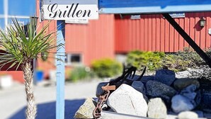 A sign reading "Grillen" above a stone wall with a palm tree and a metal gate. - 7 Person Holiday Home in Sjernaroy (Stavanger)