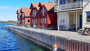 A waterfront hotel with red buildings, a wooden dock, and a lifebuoy. - 7 Person Holiday Home in Sjernaroy (Stavanger)